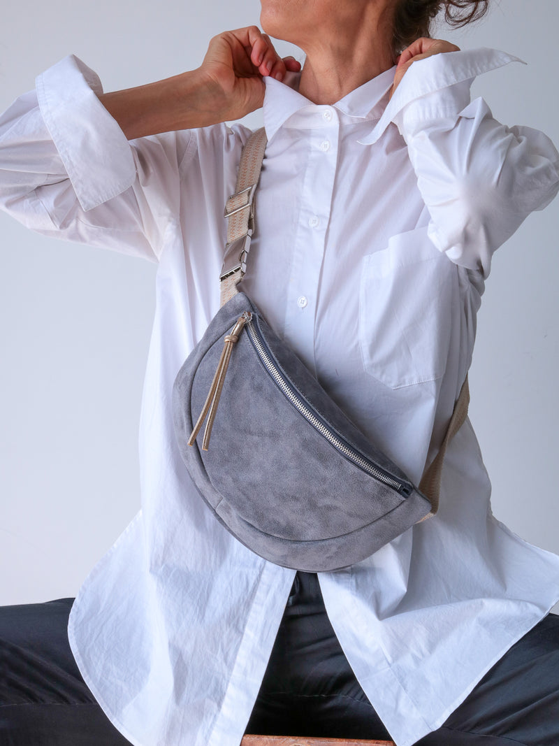 GREY SUEDE BELT BAG WITH GOLD LEATHER ZIP PULLER WORN ON A WHITE SHIRT