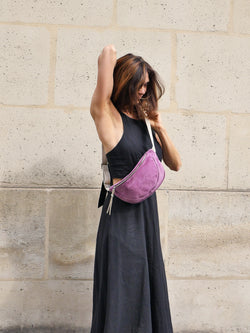 Violet suede belt bag with gold metallic leather zip puller worn by a beautiful woman in a black dress